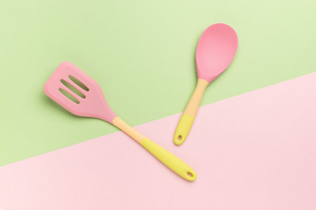 Bright silicone spatula and spoon on a two-tone background. Creative kitchen utensils.の写真素材