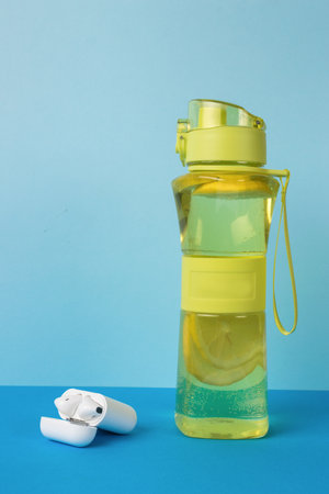 A box with wireless headphones and a sports bottle on a blue background. Sport concept.の写真素材