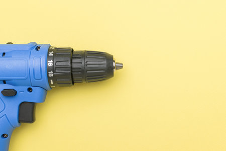 A blue screwdriver on a light yellow background. A tool for tightening screws.