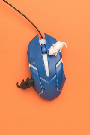 A wired computer mouse and two mouse figures on an orange background. An accessory for a personal...