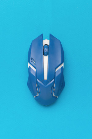 A wireless blue and white computer mouse on a blue background. An accessory for a personal computer.