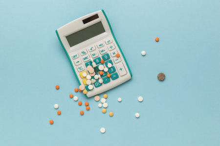 A calculator and scattered pills on a blue background. The concept of high cost of medicines.の写真素材