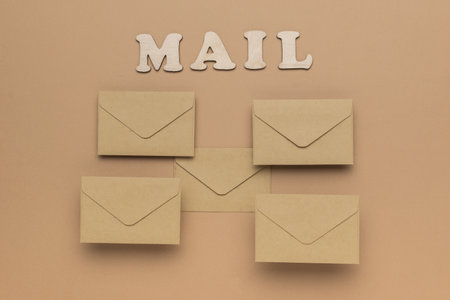 The inscription mail and five beige postal envelopes on a beige background. The concept of communication through correspondence.の写真素材