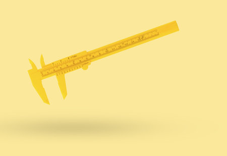 Classic yellow caliper on a yellow background. A tool for accurate measurement of dimensions.