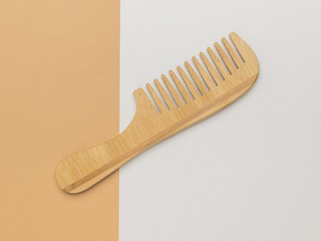 Wooden comb on beige and white background. A hair care accessory.