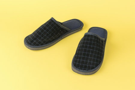 A pair of men's home slippers on a yellow background. Stylish sports shoes.
