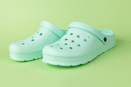 Green rubber women's shoes on a green background. Stylish sports shoes.