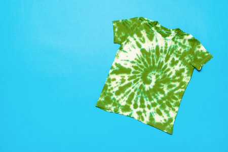 A white and green T-shirt painted in tie dye style on a blue background. The concept of making clothes with your own hands.の写真素材