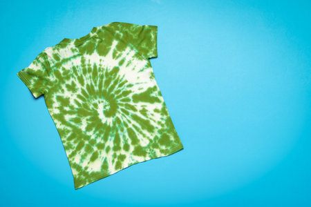 The reverse side of a white and green tie dye T-shirt on a blue background. The concept of making clothes with your own hands.の写真素材