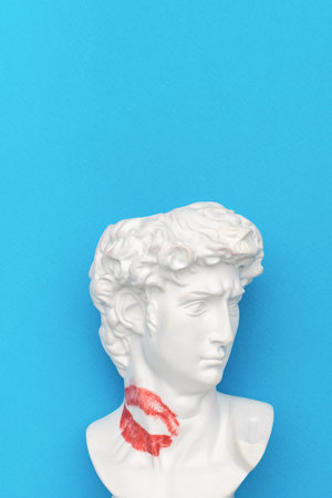 White marble bust of a historical figure featuring a red lipstick kiss mark on the neck, set against a bright blue background. ideal for creative art concepts, design, posters, and valentines themes.の写真素材