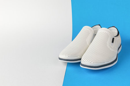 White Perforated Men's Formal Shoes on Blue and White Background Modern Fashion Footwear Stock Photoの写真素材