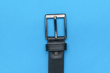Black Leather Belt with Metallic Buckle on Blue Background - Fashion Accessory Closeupの写真素材