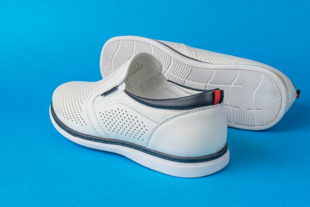 White Slip-On Shoes with Perforated Design on Blue Backgroundの写真素材