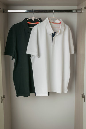 Black and White Polo Shirts Hanging in a Closet on Wooden Hangersの写真素材