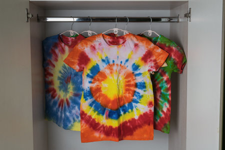 Colorful Tie-Dye T-Shirts Hanging in Closet - Rainbow Patterns and Vibrant Designsの写真素材