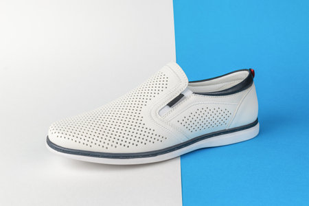 White Slip-On Shoe with Perforated Design on Split Blue and White Backgroundの写真素材