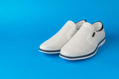 Fashionable White Slip-On Loafers on Blue Background for Modern Footwear and Style Conceptsの写真素材