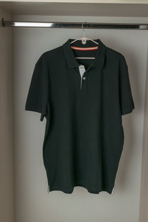 Black Polo Shirt Hanging on a Hanger in a Wardrobeの写真素材