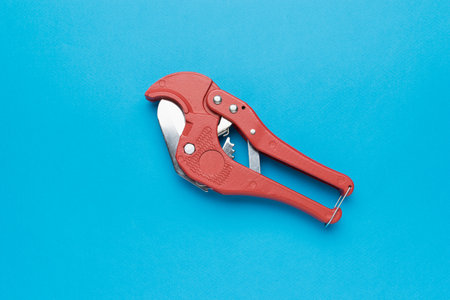 Red Pipe Cutter on Blue Background - Plumbing Tool for PVC Pipe Cuttingの写真素材