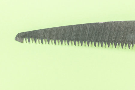 Close-Up of Sharp Saw Blade on Light Green Backgroundの写真素材