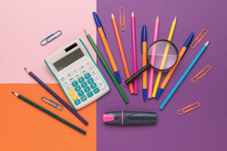Colorful Office Supplies on a Vibrant Multicolored Background with Calculator and Magnifying Glassの写真素材