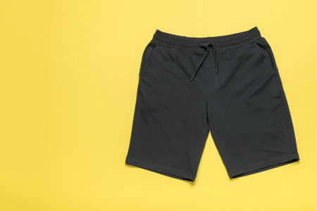 Black Casual Men's Shorts on Yellow Background Fashion, Apparel and Minimalist Design in Stock Photographyの写真素材