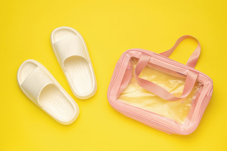 White Slippers and Pink Transparent Bag on Vibrant Yellow Backgroundの写真素材