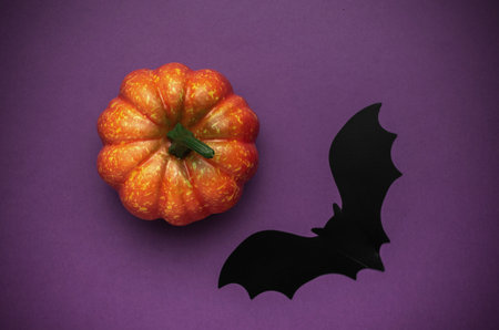 Halloween Pumpkin with Black Bat on Purple Background - Spooky Seasonal Decor Conceptの写真素材