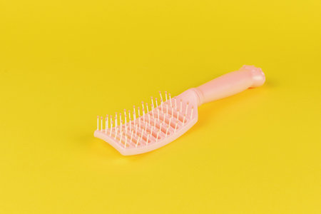 Pink Hairbrush on Yellow Background - Vibrant Pastel Colors and Beauty Essentialsの写真素材