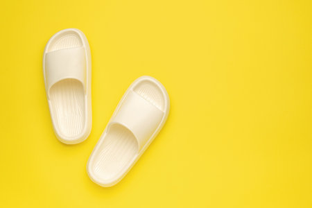Minimalist White Slippers on Bright Yellow Background - Modern Footwear Design for Fashion and Lifestyle Conceptの写真素材