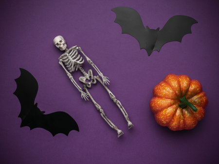 Halloween Decor with Skeleton, Bats, and Pumpkin on Purple Backgroundの写真素材
