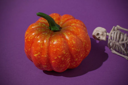 Colorful Pumpkin with Skeleton Against Purple Background Halloween Decoration and Spooky Themeの写真素材
