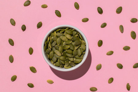 Bowl of Pumpkin Seeds on Pink Background - High Quality Stock Photo for Healthy Eating and Plant-Based Dietsの写真素材