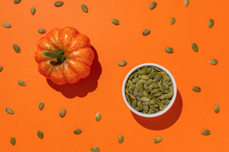 Pumpkin and Pumpkin Seeds on Orange Background - Autumn Harvest and Healthy Snacks Conceptの写真素材