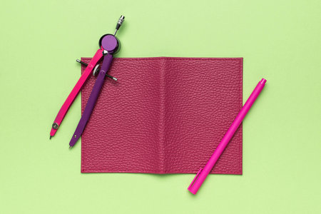 Pink Stationery on Bright Green Background: Compass, Notebook, and Penの写真素材