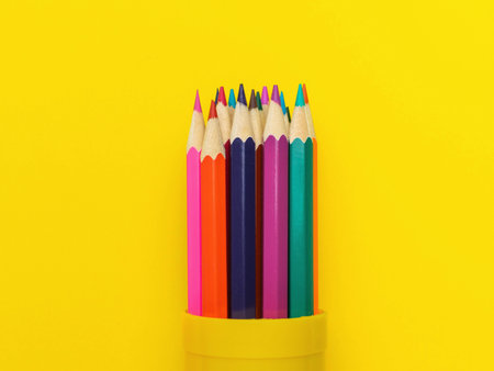 Vibrant Colored Pencils in Yellow Holder Against Bright Yellow Backgroundの写真素材