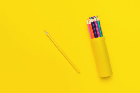 Single Yellow Pencil and Colored Pencils in a Holder on Yellow Background Minimalistic Art Suppliesの写真素材