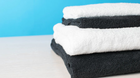 Stack of Black and White Towels on Light Wood Surface with Blue Backgroundの写真素材