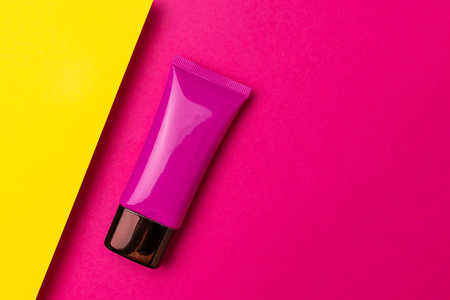 Bright Pink Cosmetic Tube on Vibrant Pink and Yellow Background - Modern Skincare Packagingの写真素材