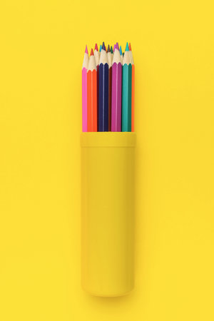Colorful Pencils in Yellow Holder Against Vibrant Yellow Backgroundの写真素材