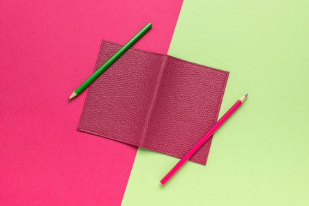 Minimalistic Leather Notebook with Pencils on Vibrant Green and Pink Backgroundの写真素材