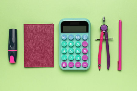 Colorful School Supplies on Green Background: Calculator, Notebook, Compass, Pen, and Markerの写真素材