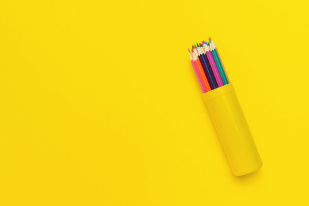 Bright Colored Pencils in Yellow Holder on Solid Yellow Backgroundの写真素材