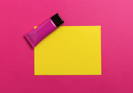 Pink Cosmetic Tube on Yellow Paper Against Bright Pink Backgroundの写真素材