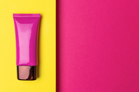 Vibrant Pink Cosmetic Tube on Bold Yellow and Pink Background - Modern Beauty Product Photographyの写真素材