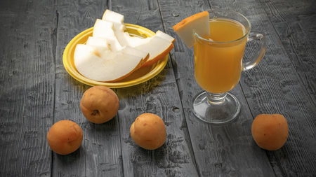 Fresh Summer Snack: Sliced Melon and Apricots with Refreshing Beverage on Rustic Wooden Tableの写真素材