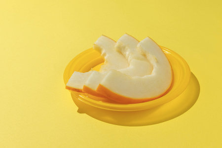 Fresh Yellow Melon Slices on Vibrant Yellow Plate in Minimalist Settingの写真素材