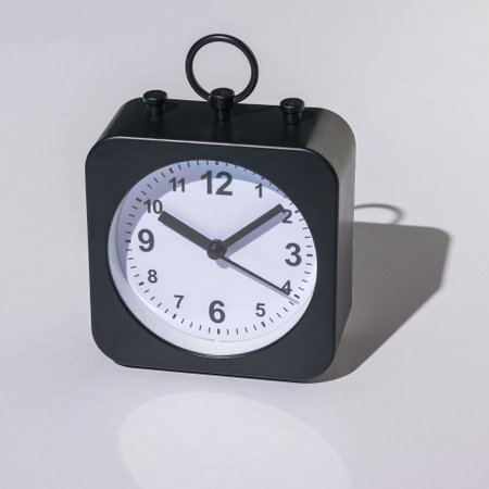 Minimalist Black Square Analog Alarm Clock on White Backgroundの写真素材