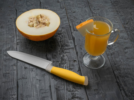 Fresh Melon Juice with Half Melon and Knife on Rustic Wooden Tableの写真素材
