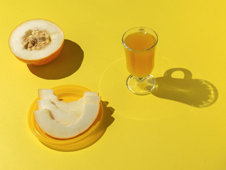 Fresh Melon and Juice on Bright Yellow Background - Vibrant and Refreshing Summer Vibesの写真素材